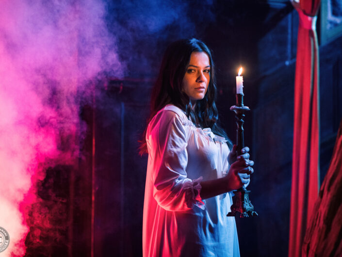 L’actrice Mathilde Cerf en chemise de nuit blanche tenant un chandelier, fumée rose et bleue, clip de BlackRain