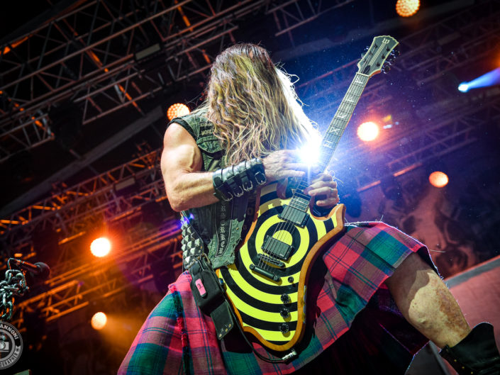 Zakk Wylde de Black Label Society en concert, guitare jaune et noire et kilt écossais, scène éclairée