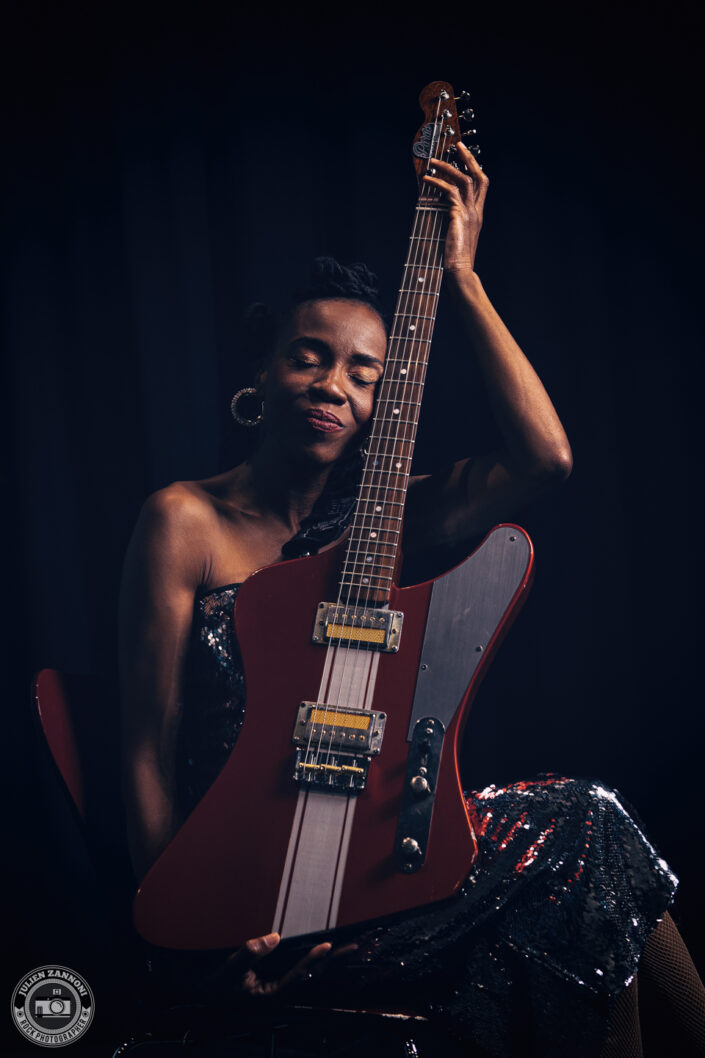 Teneia Sanders holding her electric guitar during a photoshoot – photo by Julien Zannoni.