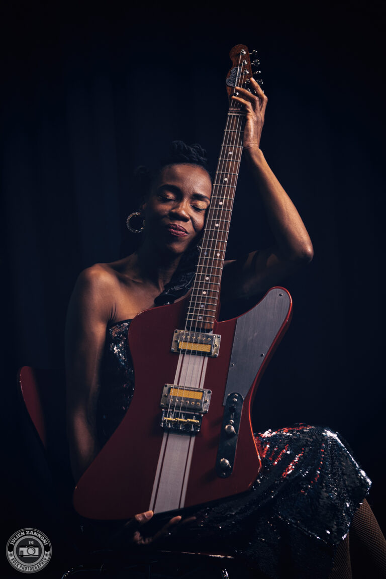 Teneia Sanders holding her electric guitar during a photoshoot – photo by Julien Zannoni.