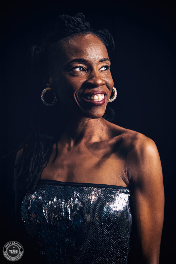 Close-up portrait of Teneia Sanders smiling during a photoshoot – photo by Julien Zannoni.