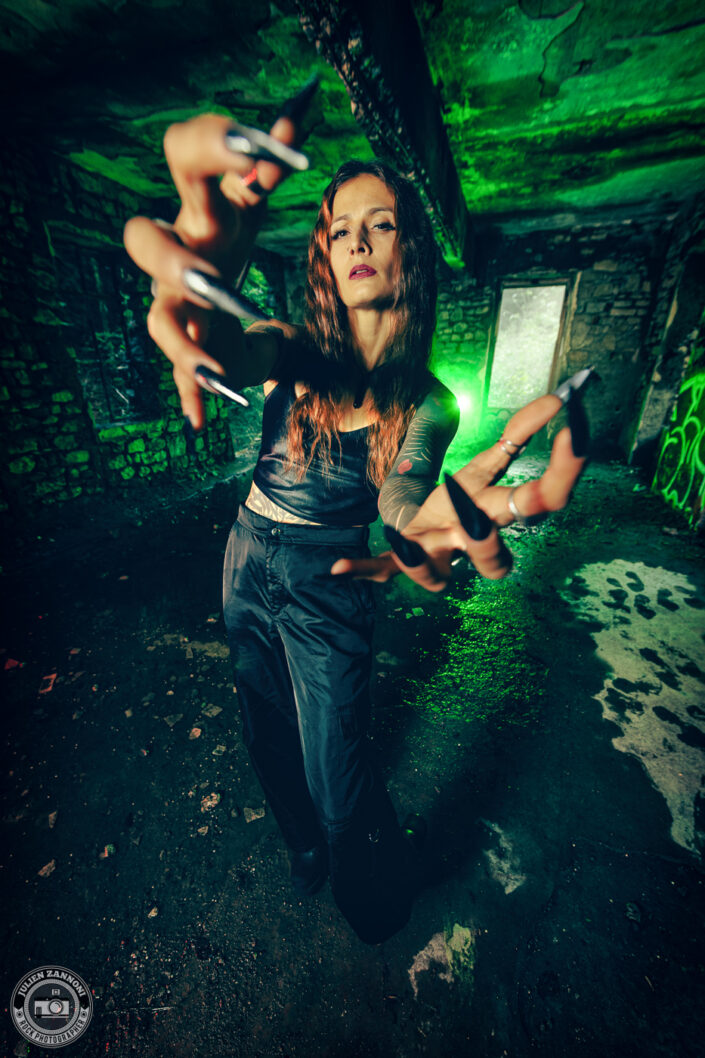 Barbara Mogore, chanteuse de Nightmare, posant dans un bâtiment abandonné éclairé en vert fluorescent.