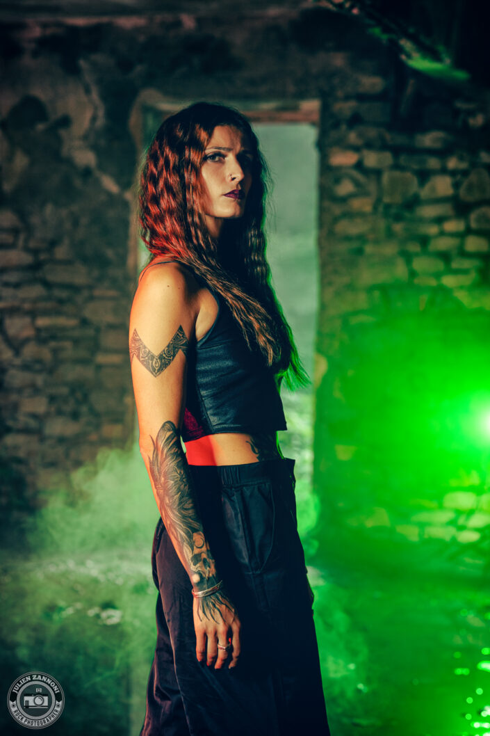 Barbara Mogore, chanteuse du groupe Nightmare, en profil dans un lieu abandonné avec une lumière verte intense.