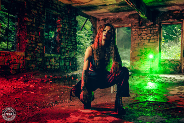 Barbara Mogore, chanteuse de Nightmare, posant dans un bâtiment abandonné avec un éclairage vert et rouge contrasté.